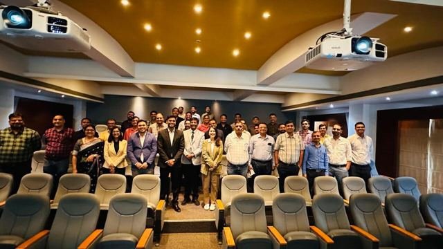 Participants standing together at the front of an auditorium after a training session